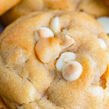 Close up shot of white chocolate macadamia nut cookies with recipe title on top of photo