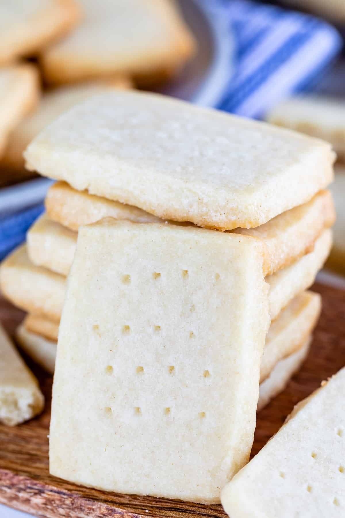 stack of shortbread cookies with one leaning against it and blue striped towel behind