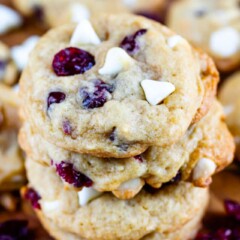 Close up shot of stacked cranberry white chocolate cookies on a wood cutting board