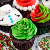 4 cupcakes decorated for christmas: snowman, Santa, swirled frosting, tree with words on photo