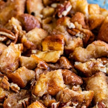 Monkey Bread in a glass baking dish with pecans on top and recipe title on top of image