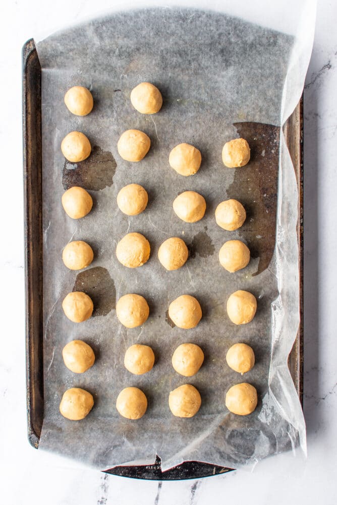 Overhead shot of peanut butter balls rolled and on a sheet pan