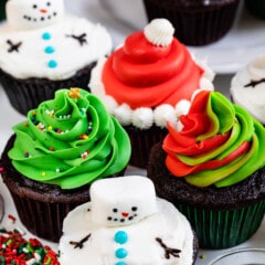 4 cupcakes decorated for christmas: snowman, Santa, swirled frosting, tree