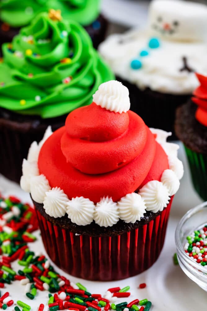 christmas cupcake decorated like a Santa hat with red frosting and white puffs
