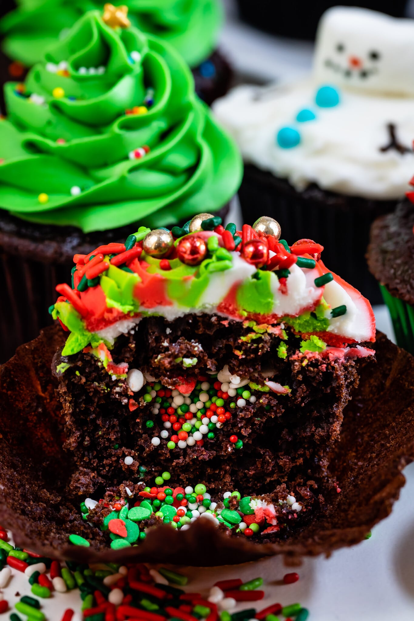 chocolate cupcake sliced open with sprinkles inside and swirled frosting