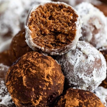 Easy rum balls stacked in a white dish with top one cut in half to show inside