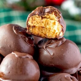 Peanut butter balls stacked on eachother with top one cut in half to show filling with recipe title on top of image