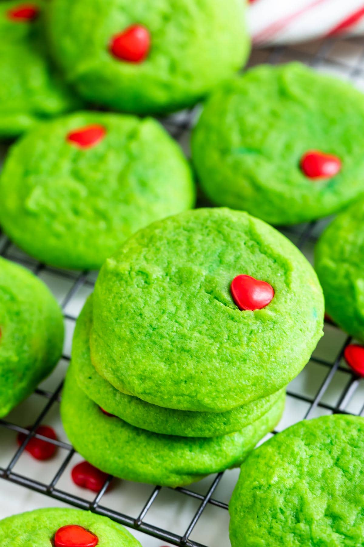 Grinch cookies stacked on a metal wire rack after cooling