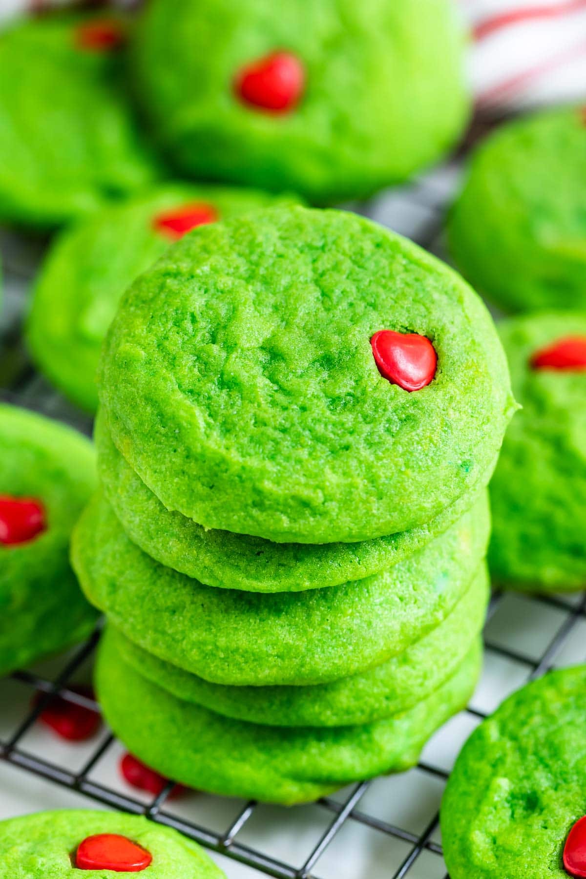 Close up photo of large stack of grinch cookies on a metal cooling rack
