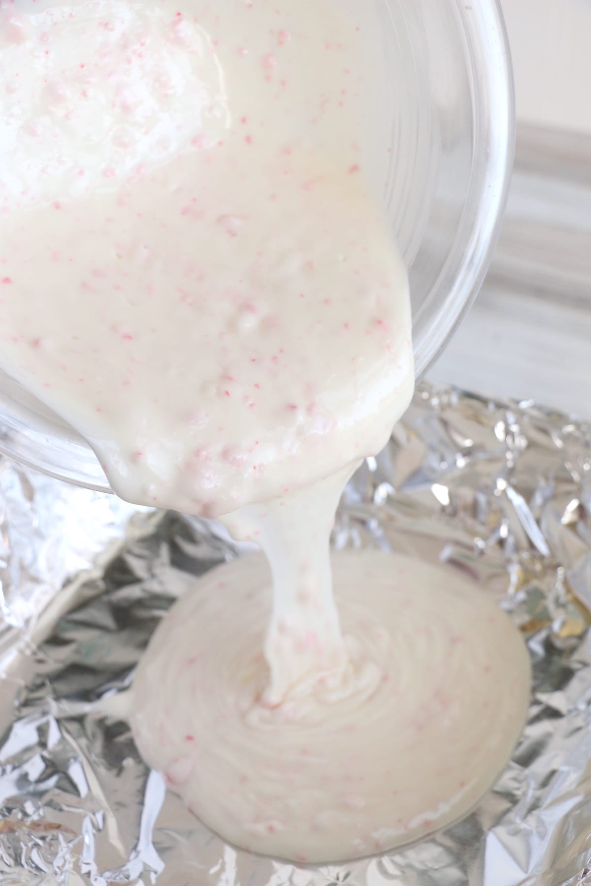 Process photo showing peppermint bark first layer being poured into foil covered pan