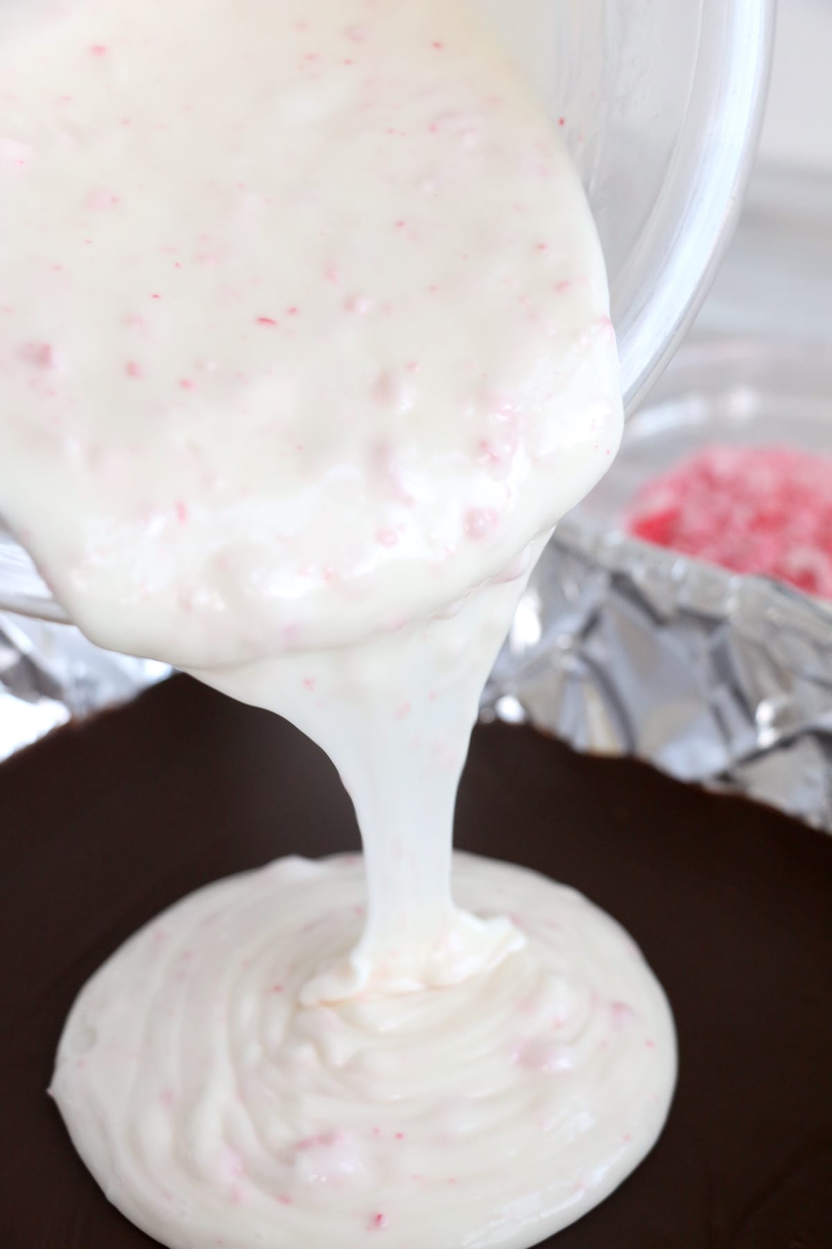 Process photo showing final white chocolate layer being poured on top of chocolate layer