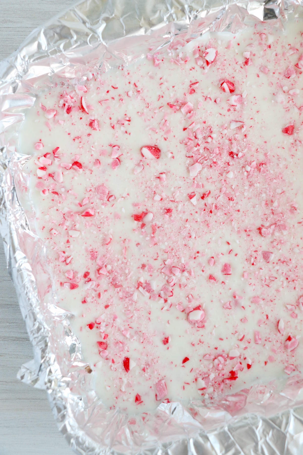 Overhead shot of peppermint bark in tin covered pan ready to set