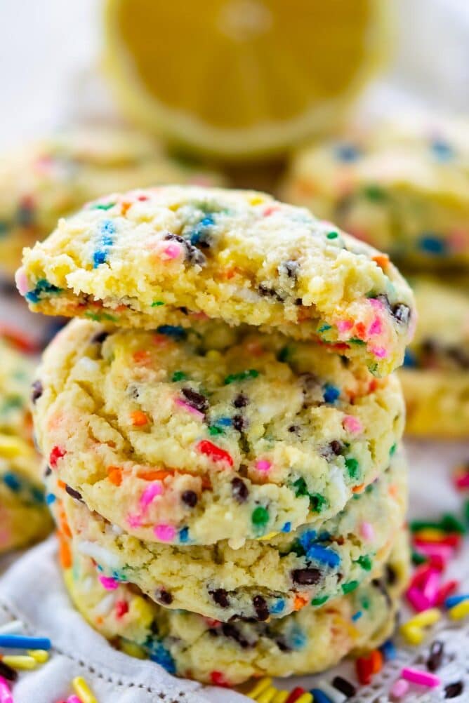 Stack of lemon cake mix cookies with top one cut in half to show sprinkles on the inside of cookie