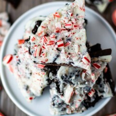 Overhead view of Oreo peppermint bark pieces on a white cake stand with candy canes and more bark below on counter