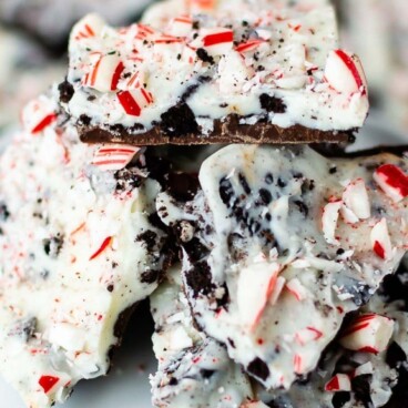 Close up shot of Oreo peppermint bark pieces on a white cake stand with recipe title on top of image