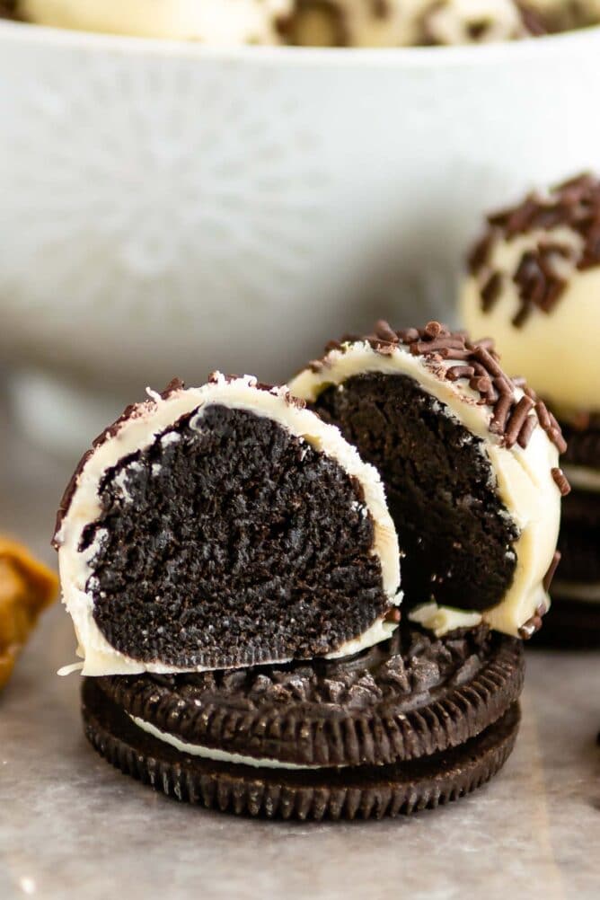 Oreo truffle cut in half sitting on top of an Oreo with more truffles in background