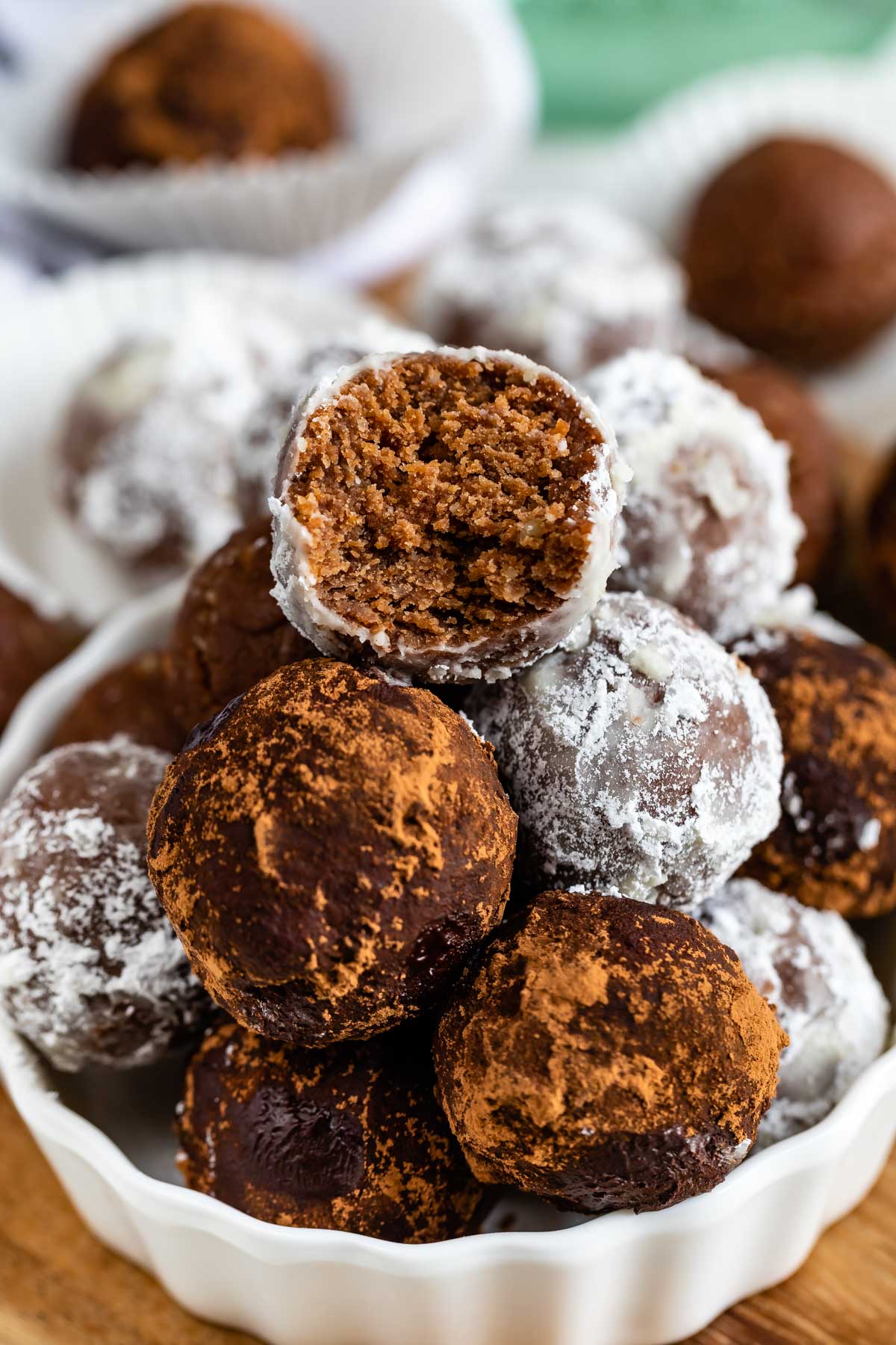 Easy rum balls stacked in a white dish with top one cut in half to show inside