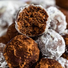 Close up shot of rum balls stacked on top of eachother with top rum ball cut in half to show inside