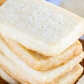 Stack of rectangular shortbread cookies on a wood cutting board with recipe title on top of image