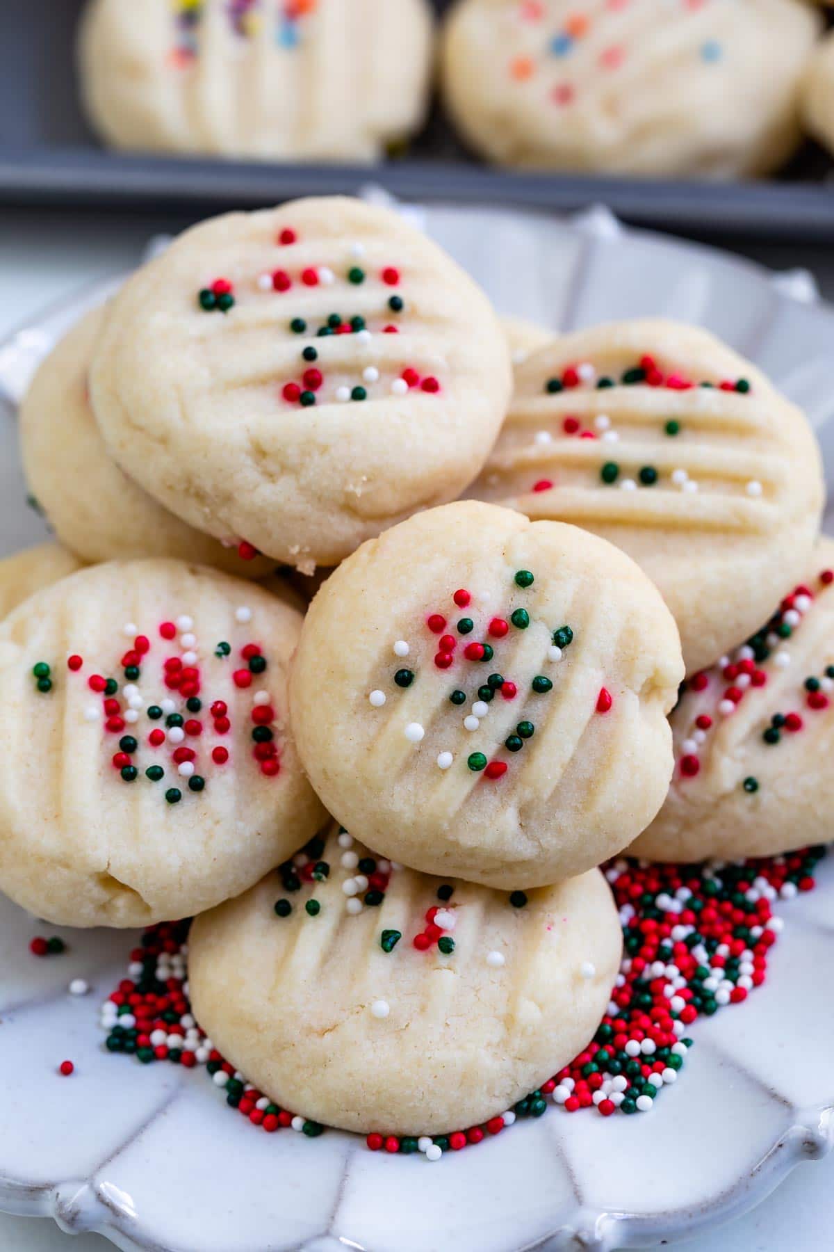 stack of whipped shortbread on plate with christmas nonpareils