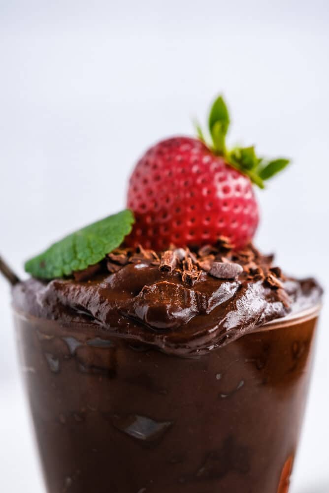 Close up side shot of avocado chocolate mousse with a cherry and mint on top