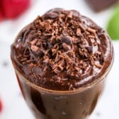 Overhead close up shot of avocado chocolate mousse in glass pudding dish with chocolate shavings on top