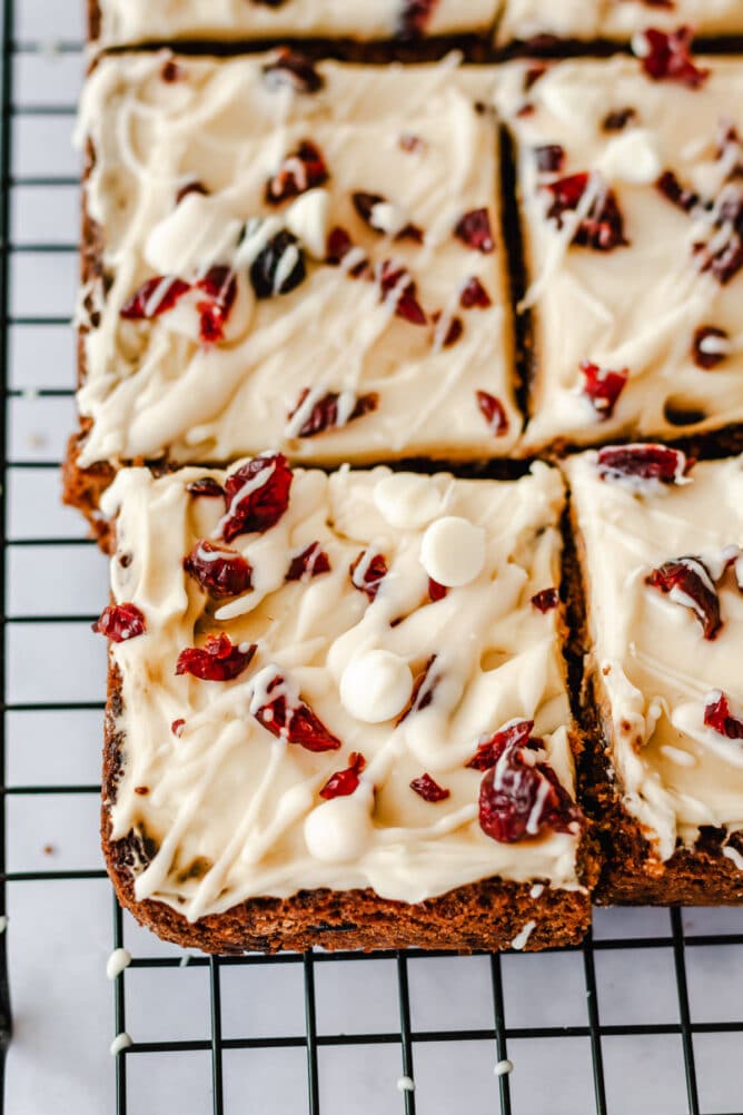 Overhead view of cranberry bliss bars on a metal cooling rack cut into squares