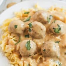 Plate full of swedish meatballs over egg noodles with recipe title on top of image