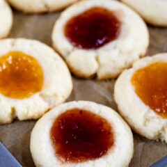 Jam thumbprint cookies on a cookie sheet with parchment paper
