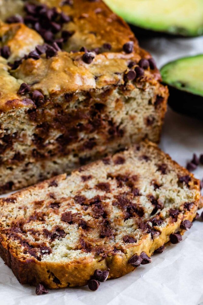 One slice of avocado banana bread cut from the main loaf and flat on the counter