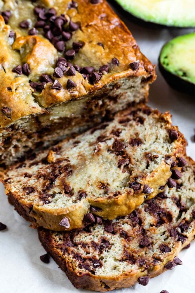 Two slices of avocado banana bread in front of the whole loaf