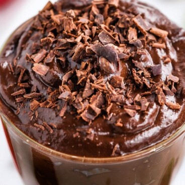 Overhead shot of avocado chocolate mousse with chocolate shavings on top and recipe title on top of image