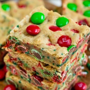 Overhead view of three christmas cookie bars stacked on eachother with m&ms all around