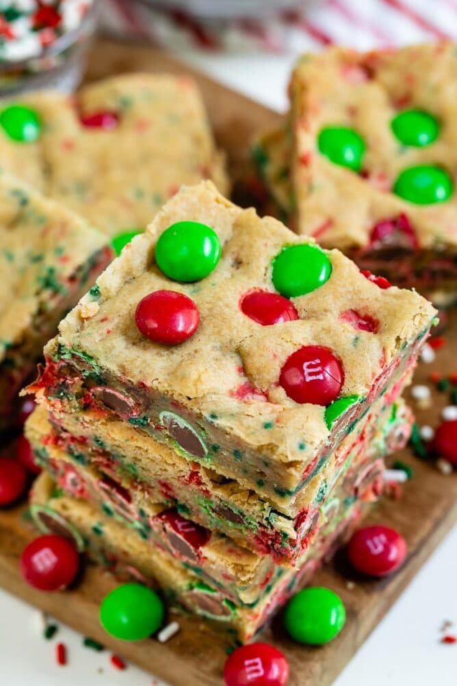 Overhead view of three christmas cookie bars stacked on eachother with m&ms all around