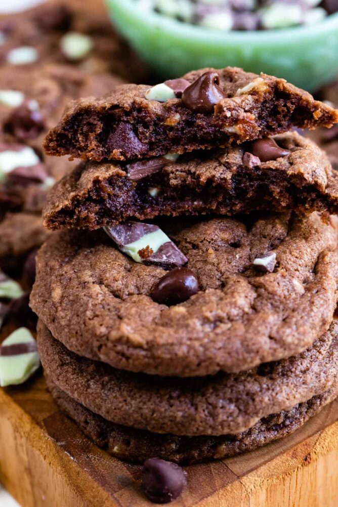 Double chocolate mint cookies stacked on eachother with top cookie broken in half to show inside