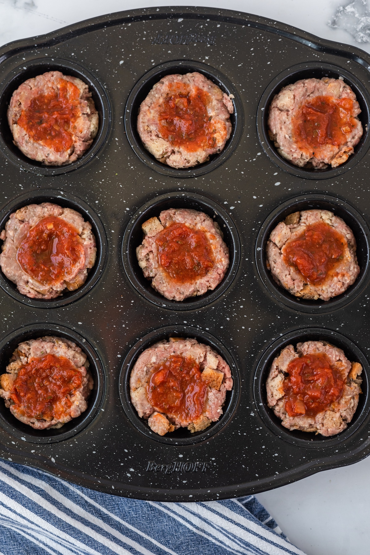 Overhead shot of mini meatloaves in a muffin tin ready to be baked