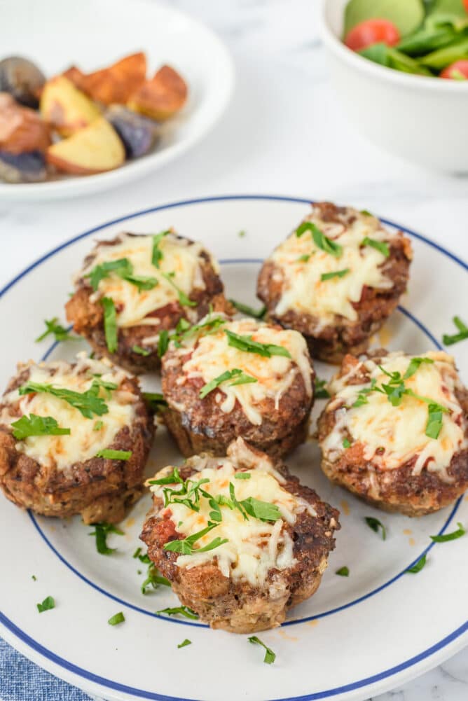 Six mini meatloaves on a plate with cheese on top