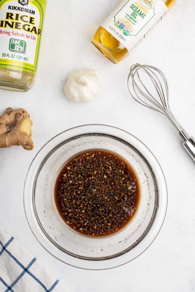 Overhead view of teriyaki sauce in bowl with whisk and ingredients around it