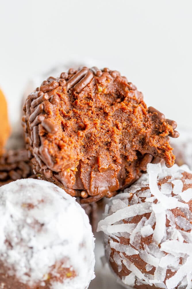 Close up of chocolate avocado truffles with top one cut in half to show inside filling