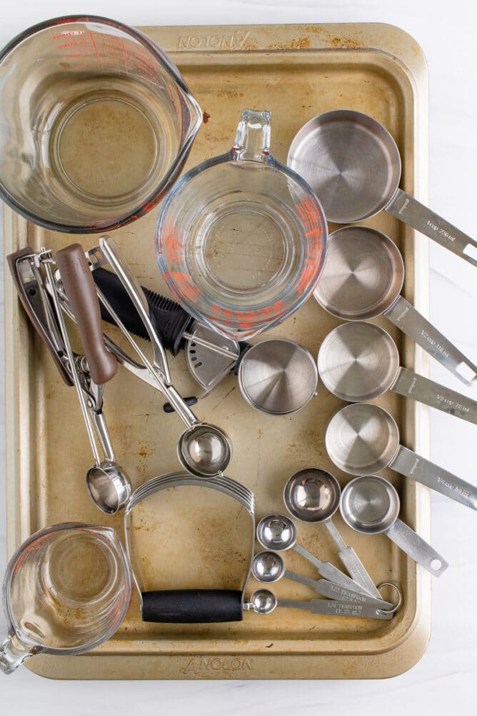 Overhead view of must have baking tools spread out on a gold sheet pan