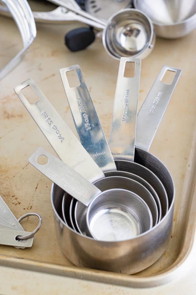 Close up shot of stainless steel measuring cups in corner of sheet pan