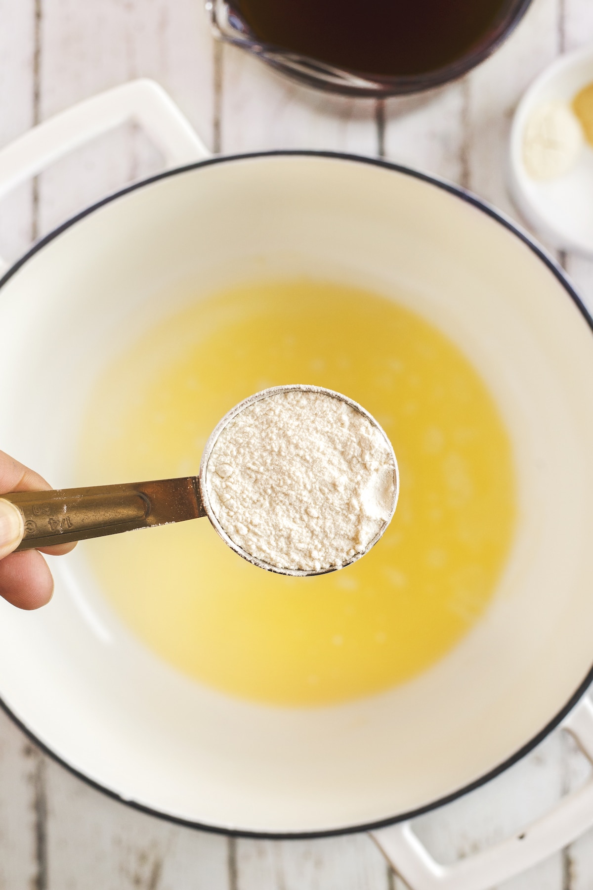 pot with stock and cornstarch being held over it in teaspoon.