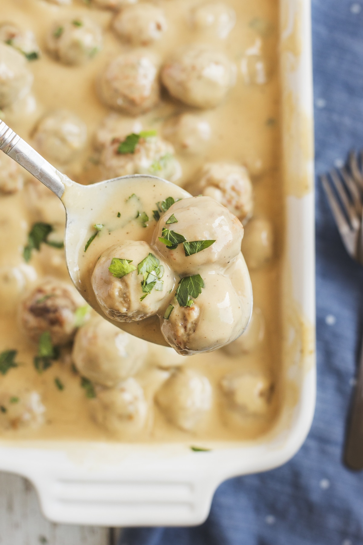 meatballs on spoon held over casserole dish.