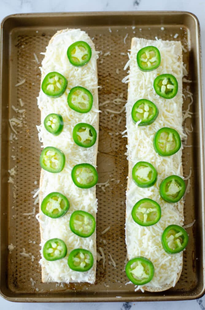 Overhead shot of two loaves of jalapeno cheese bread on a sheet pan ready for the oven