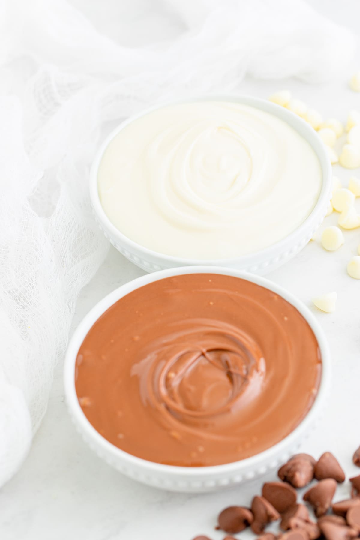 Overhead shot of melted white chocolate and milk chocolate in small white bowls