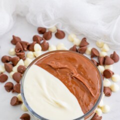 Bowl filled with half melted white chocolate and half melted milk chocolate with chocolate and white chocolate chips around it