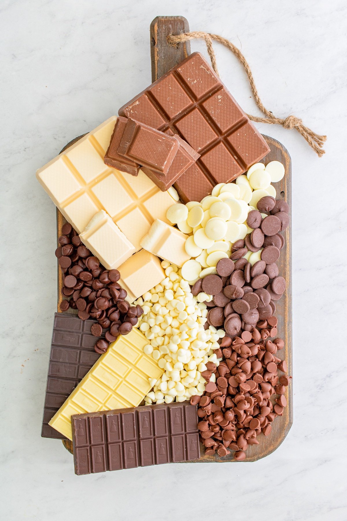 overhead shot of different kinds of chocolate on wood cutting board with words on photo