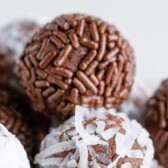 Close up shot of chocolate avocado truffles with sprinkles and coconuts on the outside with recipe title on top of image