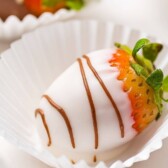 Close up shot of white chocolate covered strawberry with milk chocolate drizzle and recipe title on top of image