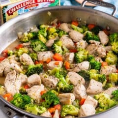 garlic butter chicken and vegetables in skillet with butter behind